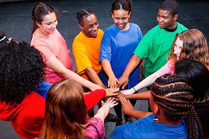 Students join hands at the center of a circle