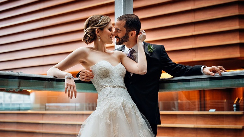 A bride and groom share an intimate moment while standing along one of the Kimmel Center's balconies.